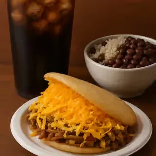 Open-faced arepa with shredded meat, cheese, iced soda, rice, beans.