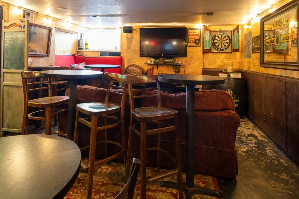 Rustic pub interior with dark wood, red booths, Jameson and Guinness posters.