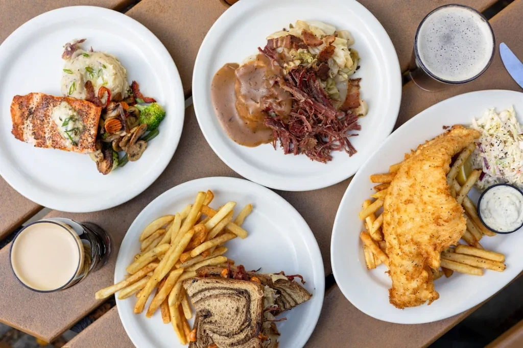 Overhead view of four pub food plates and two dark beers.