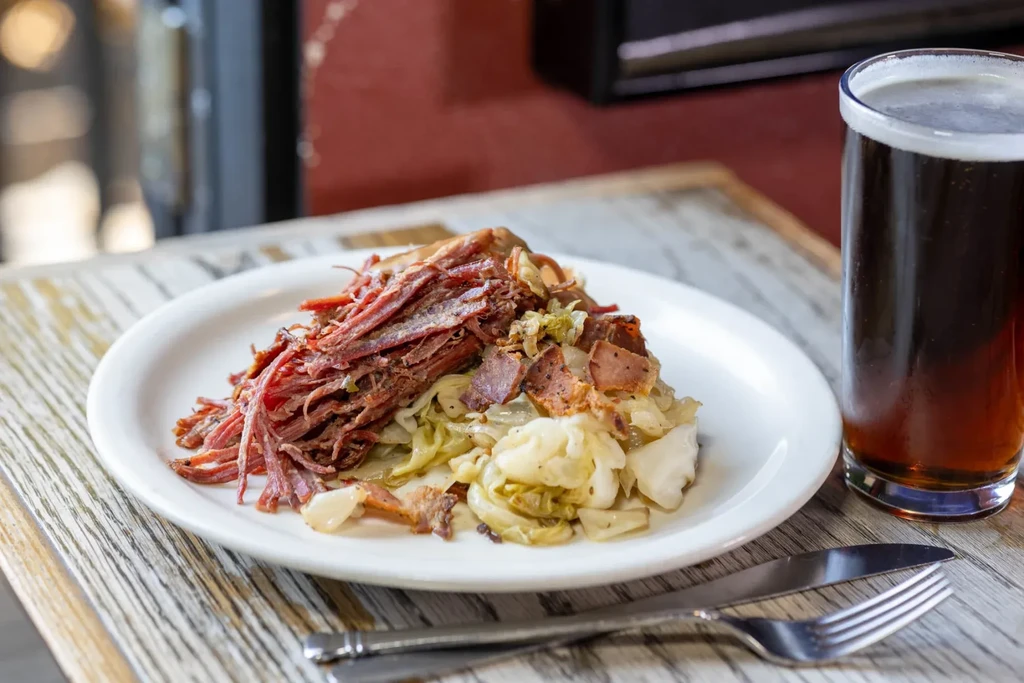 Close-up of shredded meat, cabbage, and beer on a rustic table.
