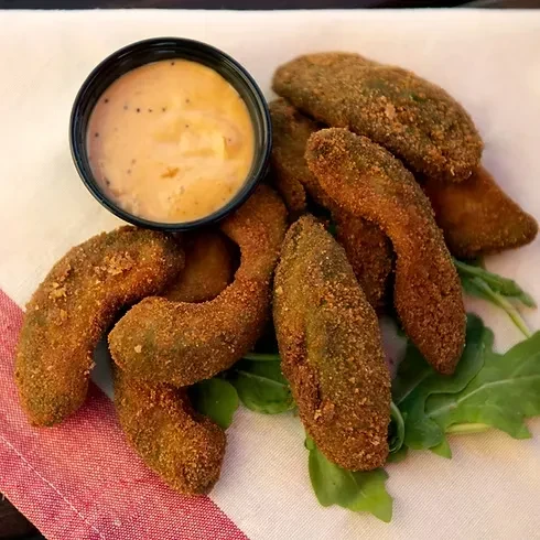 Golden fried slices with creamy dipping sauce, garnished with greens.
