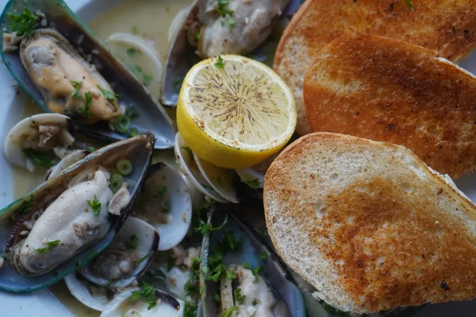 Mussels and clams in broth, grilled lemon, and toasted bread.