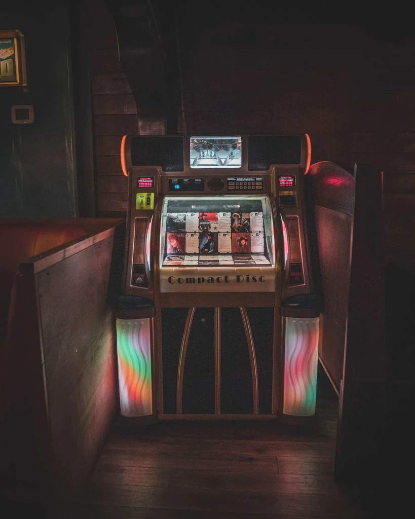 Classic illuminated jukebox with colorful lights in a dim restaurant.