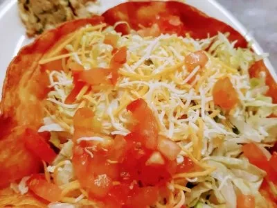 Taco salad in a fried tortilla bowl with lettuce, tomatoes, cheese.