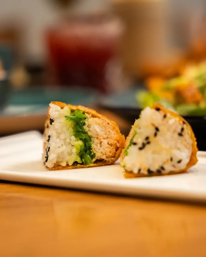 Halved fried tofu pockets revealing layered rice, green, and shredded fillings.