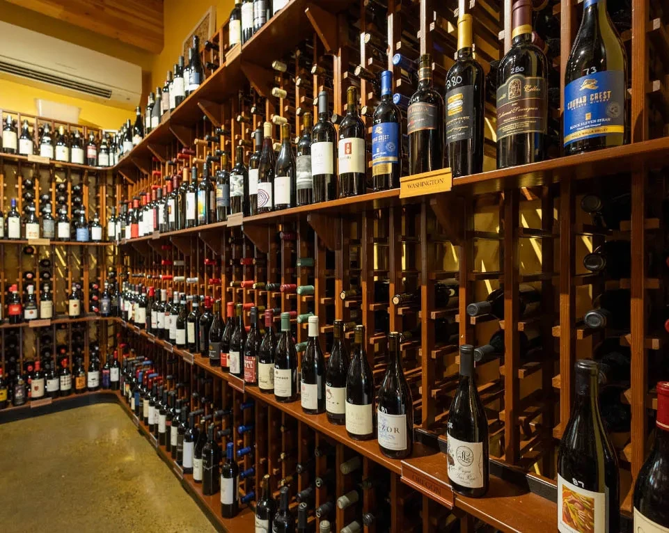 Well-stocked wine cellar with rows of red and white bottles.