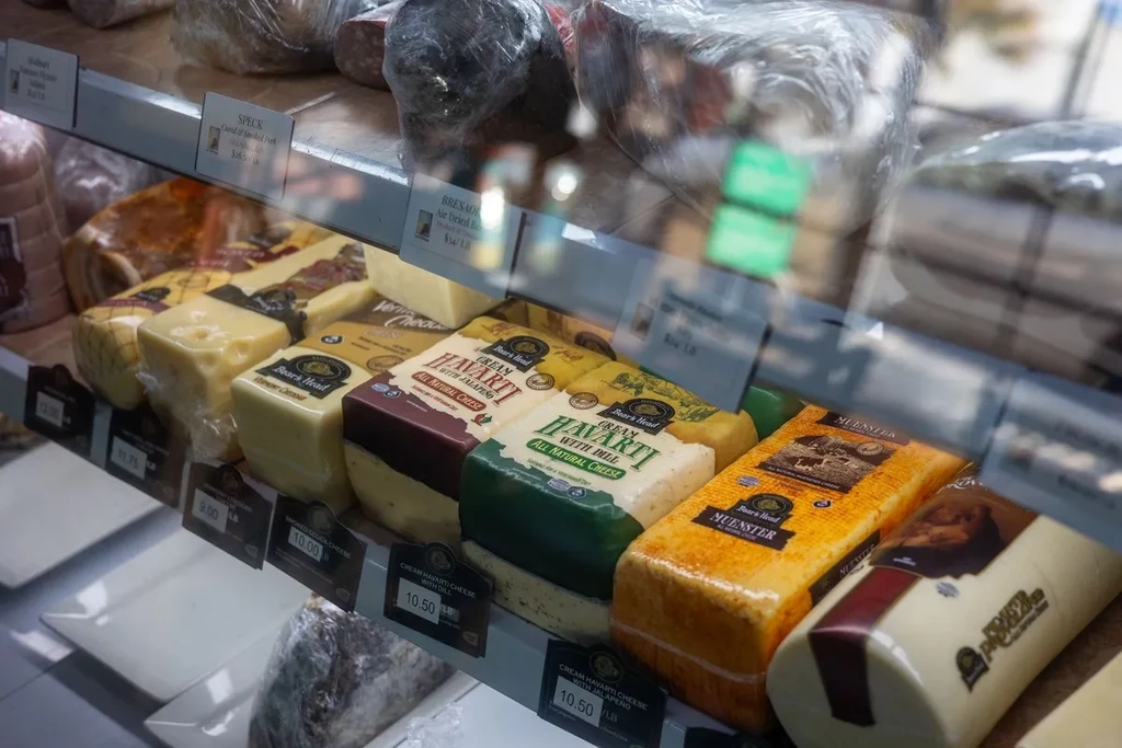 A well-stocked deli counter with various cheeses and cured meats.