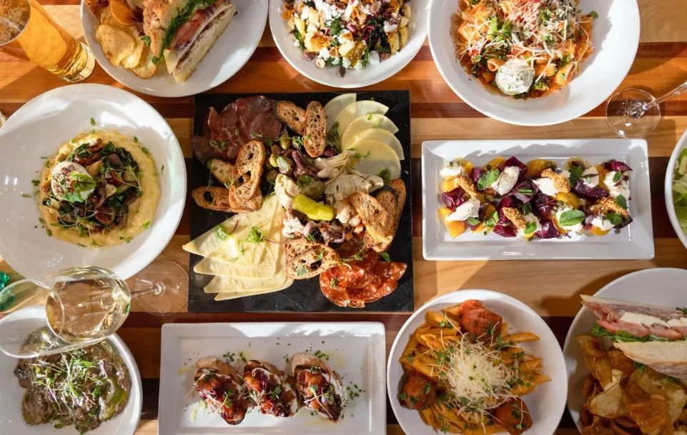 Overhead shot of a diverse food spread including charcuterie, pasta, and drinks.