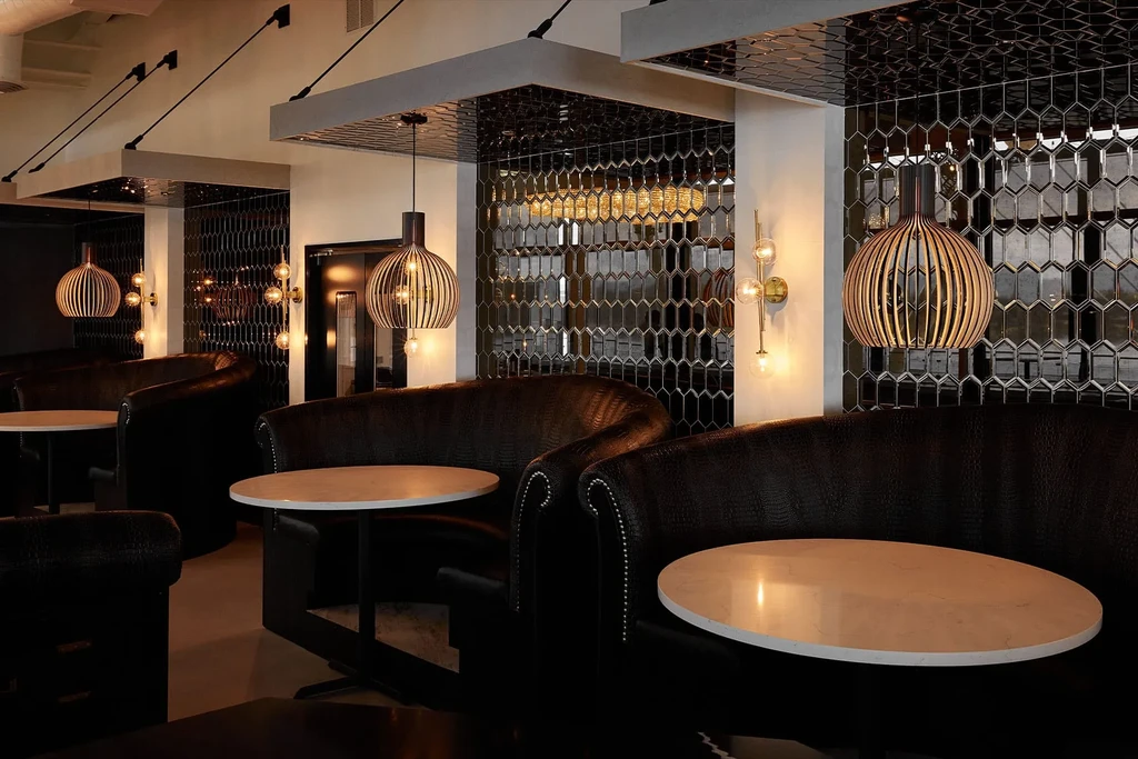 Upscale restaurant interior with dark leather booths, marble tables, and warm lighting.