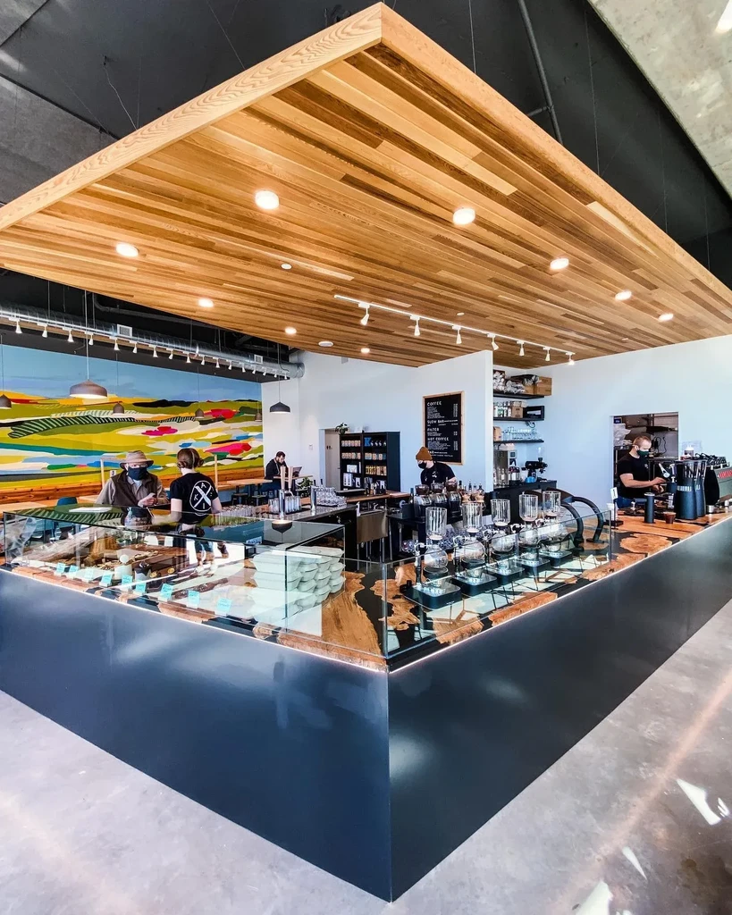 Modern cafe interior with sleek counter, slatted wood ceiling, and staff.