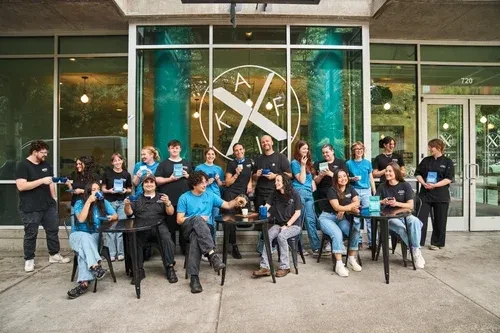 Smiling team of 16-18 staff pose at a modern KAF storefront.
