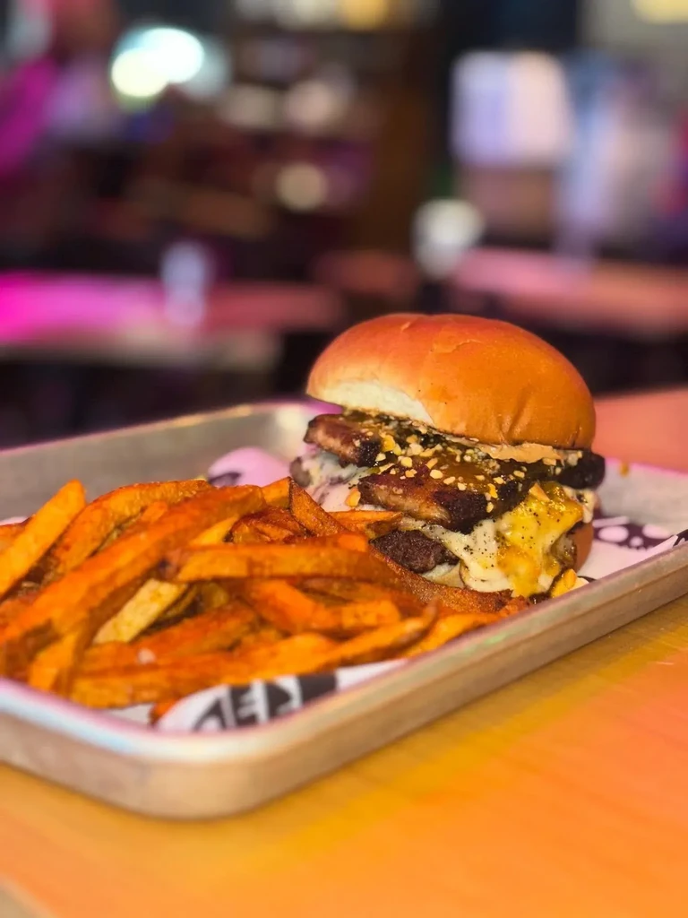 Close-up: Double burger with melted cheese, bacon, and golden fries.