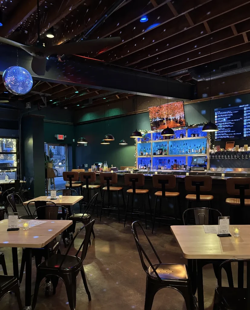 Empty, dimly lit restaurant bar with blue-lit shelves and disco ball.