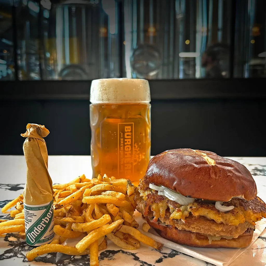 Close-up of a burger, fries, and beer at a brewery.