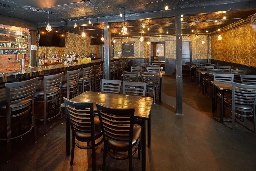 Cozy bar and restaurant interior with dark wood and warm lighting.