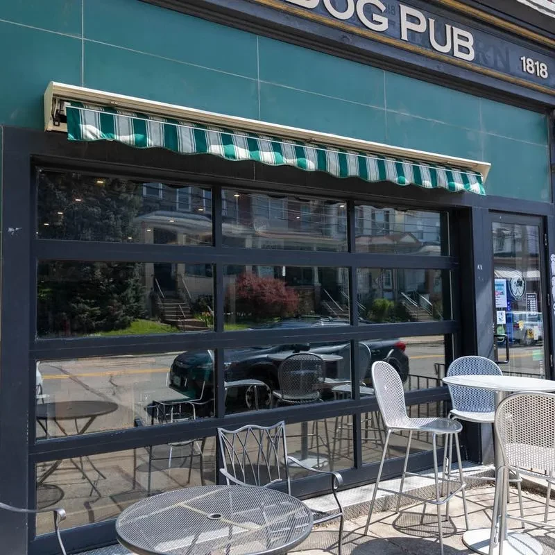Exterior of Dog Pub 1818 with green facade and outdoor seating.