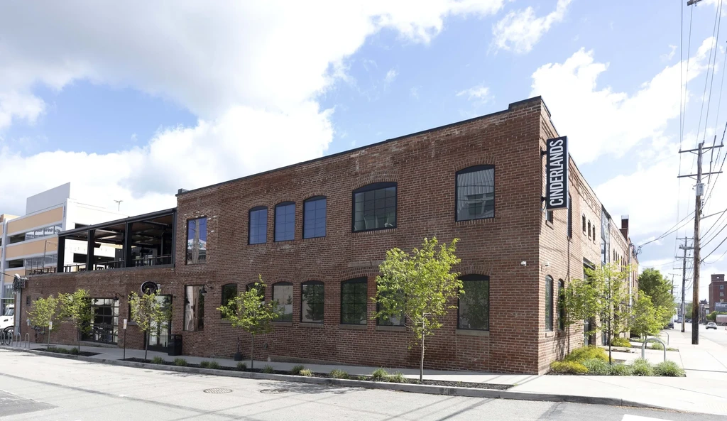 Multi-story brick CINDERLANDS building with vertical sign and upper patio.