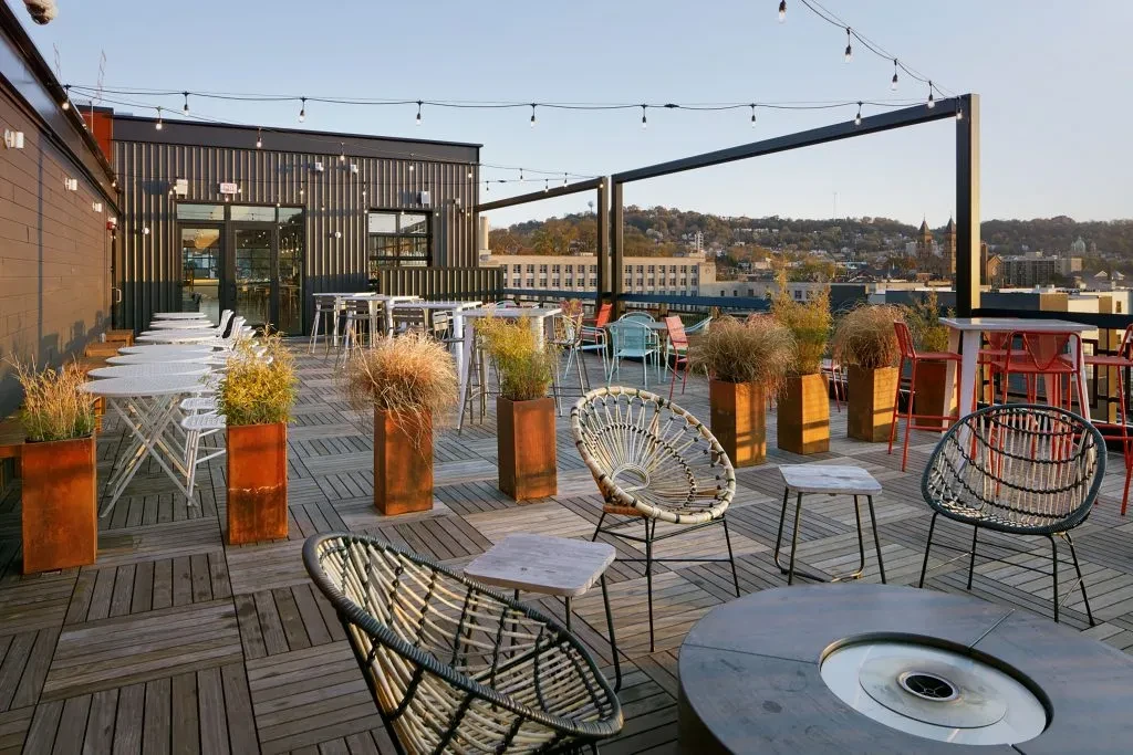 Rooftop restaurant patio with diverse seating, fire pit, and city view.