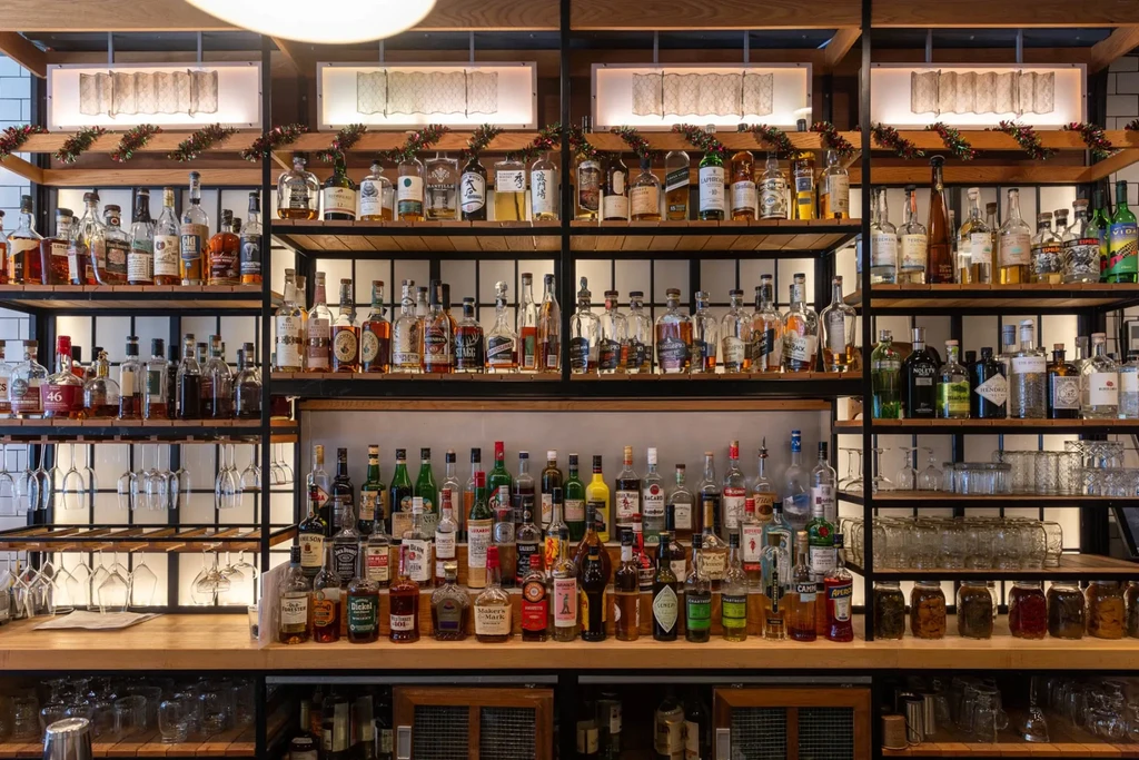 Modern, well-stocked bar displaying spirits, glassware, and holiday garlands.
