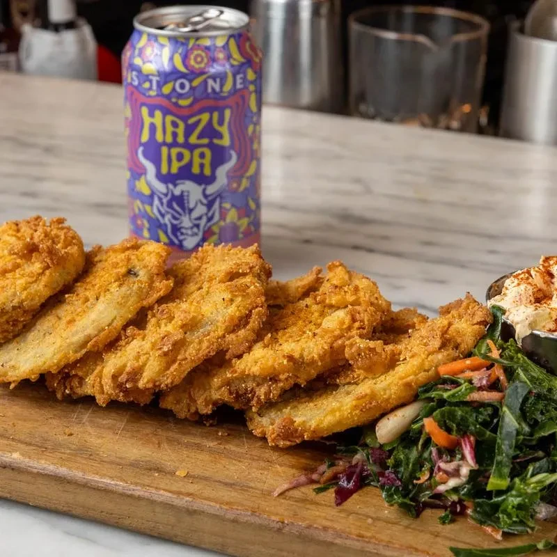 Close-up of fried food, side salad, dip, and Stone Hazy IPA beer.