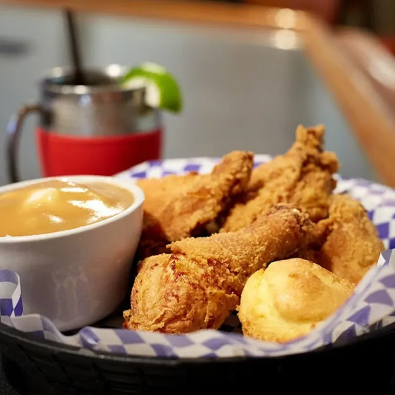 Basket of golden-brown fried chicken, biscuit, and gravy.