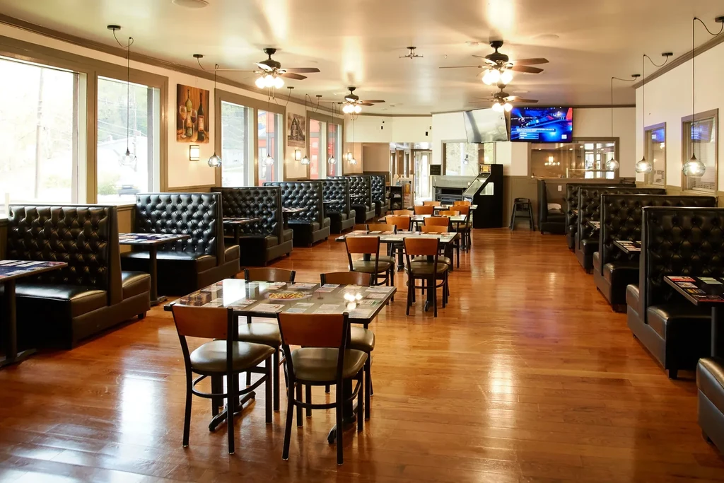 Spacious restaurant dining room with leather booths, wooden tables, and natural light.