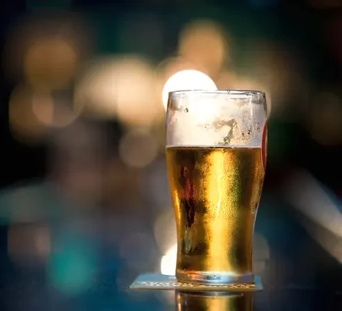 Golden beer in a cold pint glass on a dark coaster.