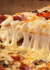 Close-up: Pizza slice lifted, gooey cheese stretching with ham and mushrooms.