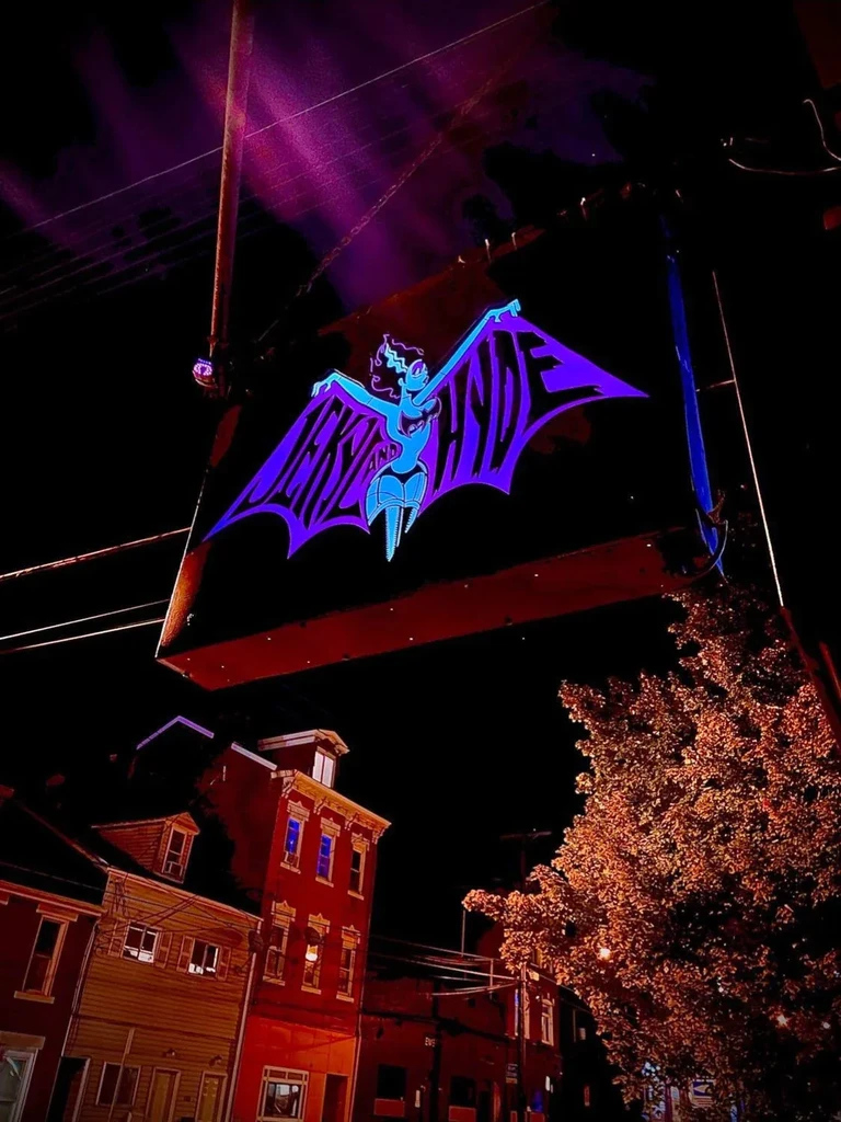 Purple and blue 'Jekyll and Hyde' neon sign with bat wings at night.