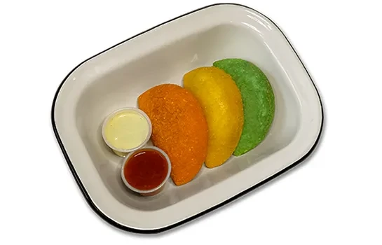 Three colorful crescent pastries in a tray with two dipping sauces.