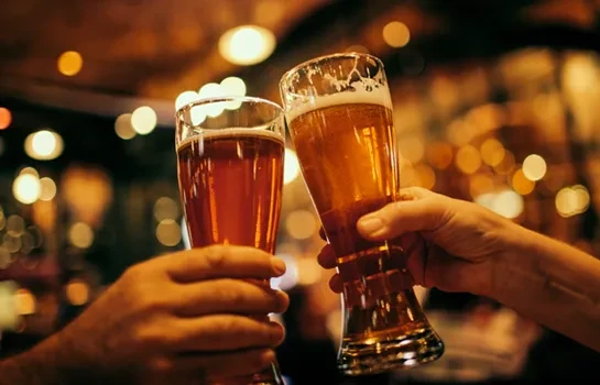 Two hands clinking glasses of dark ale and golden lager.