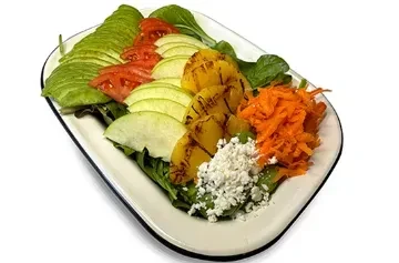 Colorful salad with avocado, tomatoes, apple, grilled pineapple, carrots, and cheese.