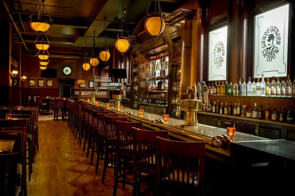 Dimly lit Gandy Dancer Saloon with long bar, stools, and liquor bottles.