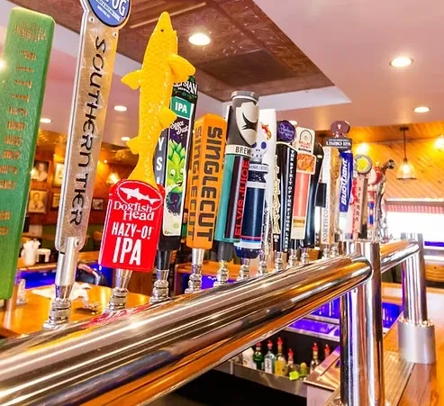 Close-up of diverse beer tap handles on a shiny bar system.