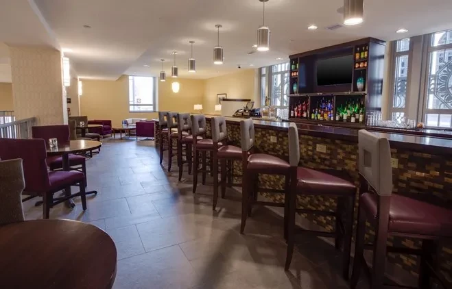 Empty modern bar and lounge with dark wood and burgundy seating.