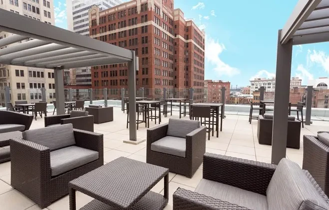 Expansive rooftop terrace with modern lounge and bar furniture, city views.