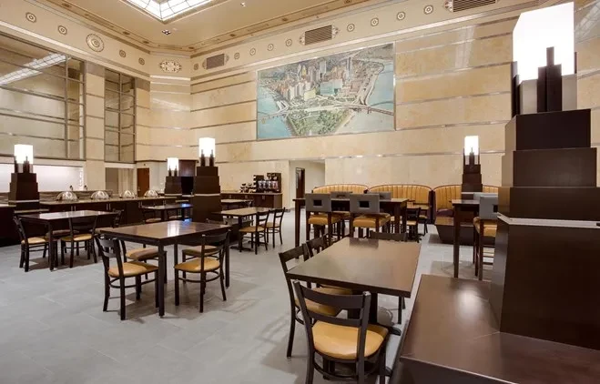 Well-lit restaurant interior with tables, booth, buffet, and city mural.
