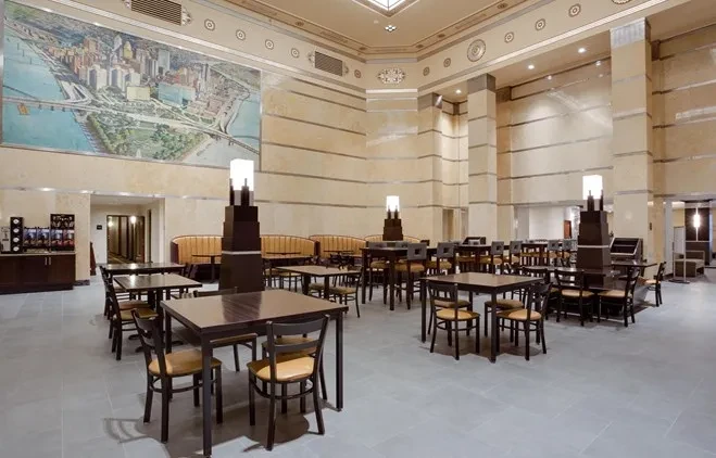 Spacious Art Deco dining room with cityscape mural, no people.