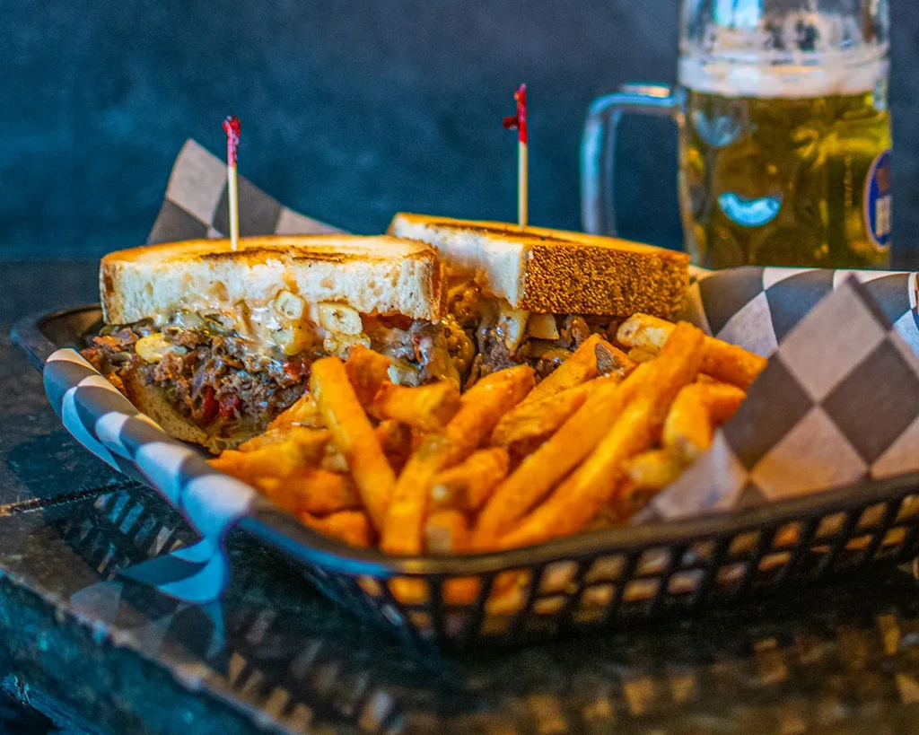 Melted cheese sandwich halves, fries, and a beer in a basket.