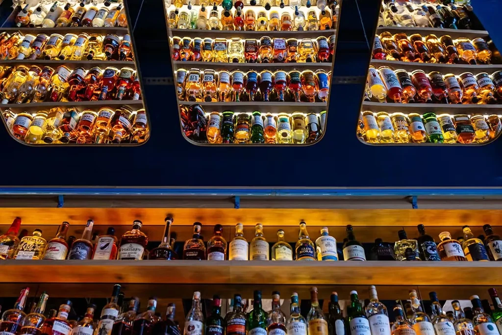 Brightly lit bar display with many colorful liquor bottles.