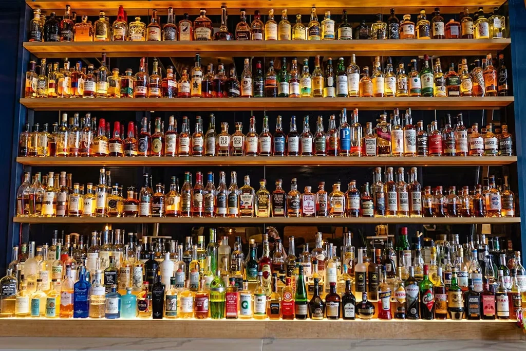 High-end bar shelves displaying a wide, illuminated liquor selection.