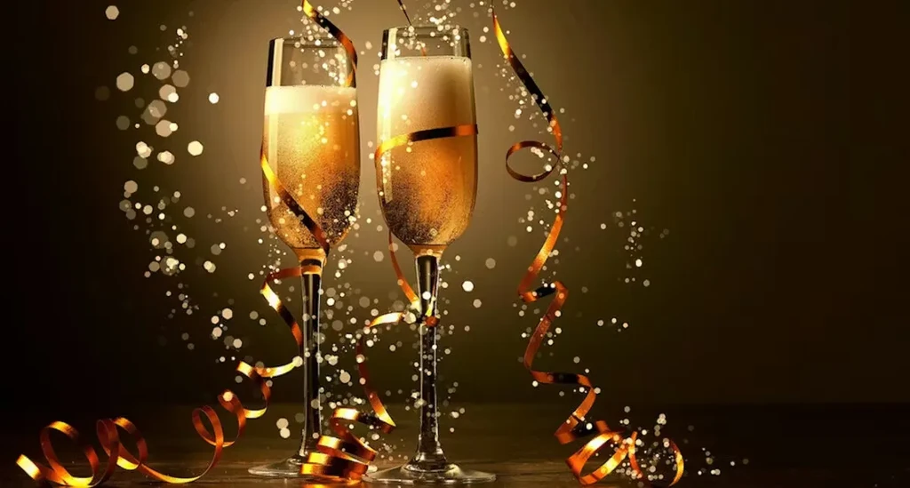 Two champagne flutes, golden liquid, orange-gold ribbons, sparkling background.