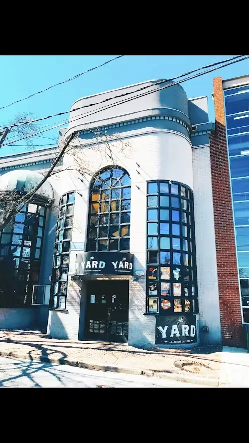 White brick Art Deco building, "THE YARD" restaurant, sunny day.