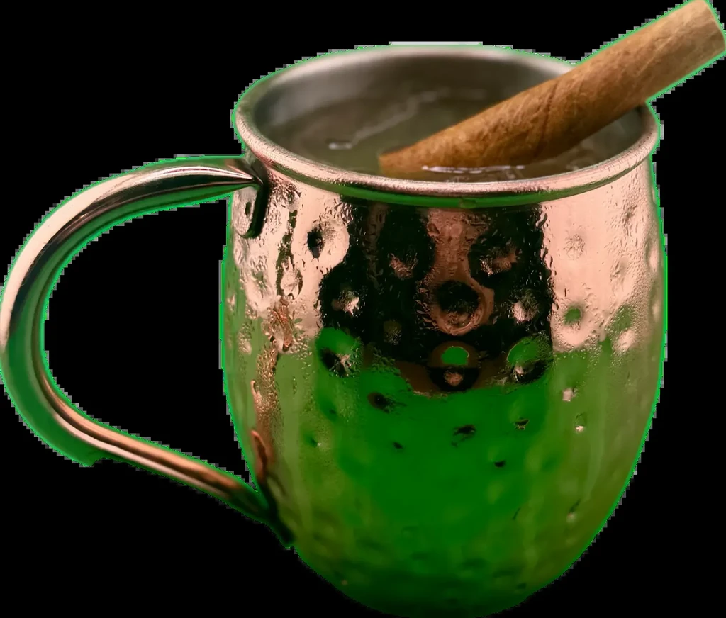 Hammered copper Moscow Mule mug with condensation, cinnamon stick, black background.