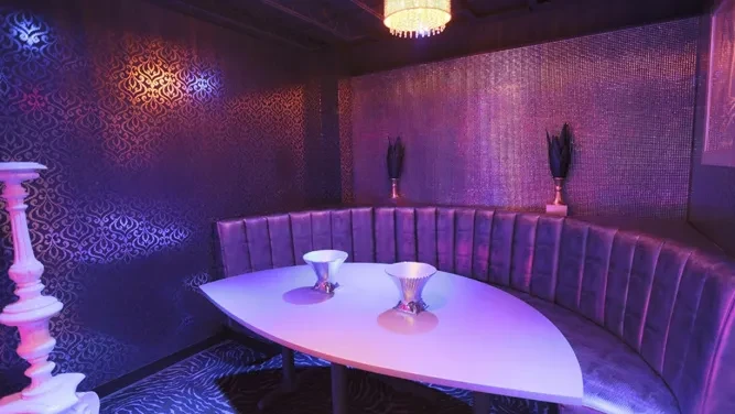 Plush purple booth, white table, and dramatic blue-purple lit restaurant interior.