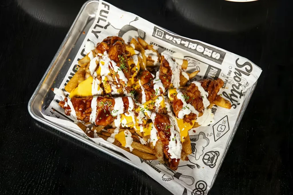 Loaded fries topped with fried chicken, cheese, two sauces, and herbs.