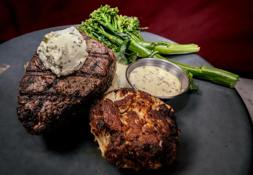 Grilled steak with herb butter, roasted cauliflower, broccolini, and sauce.