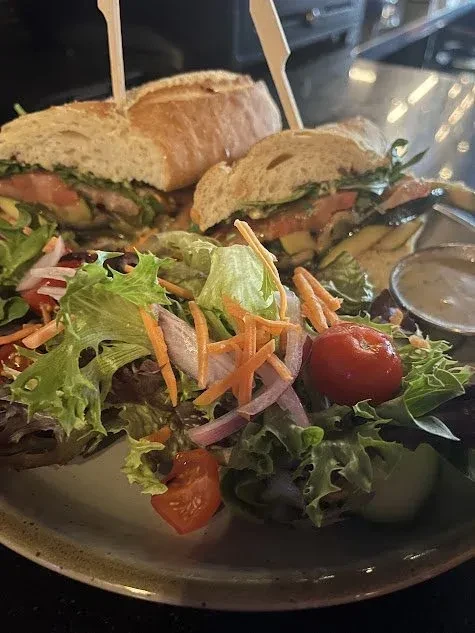 A large sandwich cut in half, with a side salad.