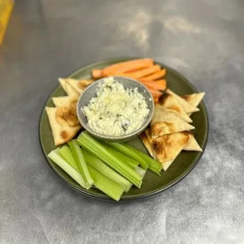 Appetizer plate with creamy dip, toasted pita, celery, and carrots.