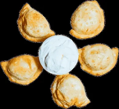 Five crispy golden-brown empanadas surrounding a central white dip.